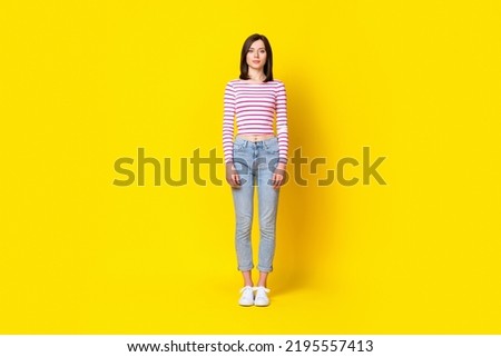 Full body photo of gorgeous cute young girl standing straight front view wear trendy striped look isolated on yellow color background