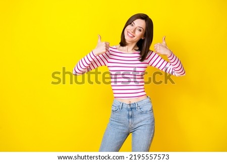 Photo portrait of winsome young lady show double thumb up good job encourage wear trendy striped outfit isolated on yellow color background