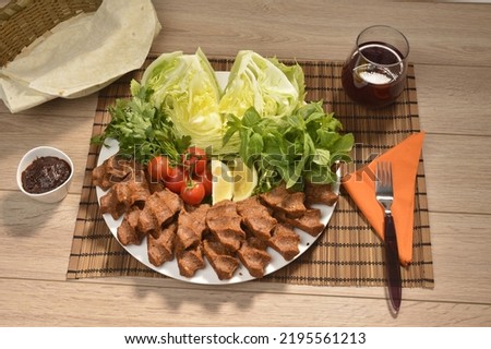 Round porcelain plate and lettuce, presentation of raw meatballs (cigkofte) with tomatoes, adiyaman