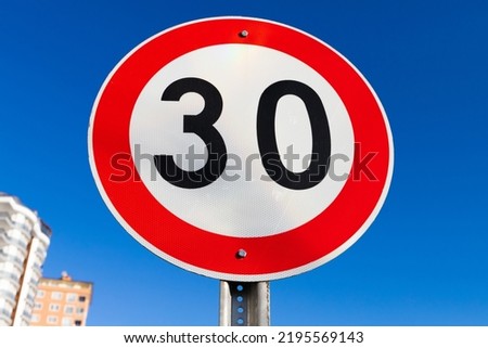 Round speed limit road sign is under blue sky