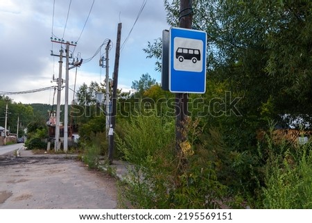 Empty bus stop with blue road sign, rural public transportation background