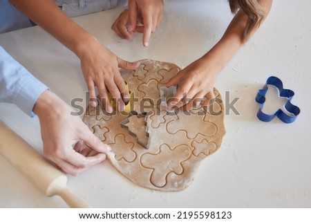 Close up picture of a young child's hand pressing a heart shape cookie cutter into soft rolled out dough to make sugar cookies.