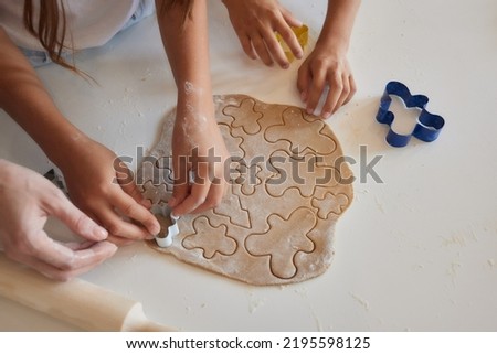 Close up picture of a young child's hand pressing a heart shape cookie cutter into soft rolled out dough to make sugar cookies.