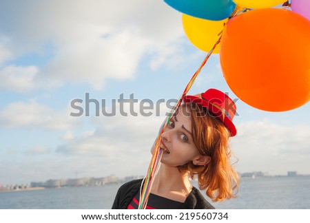 girl with an air of multicolored balls on the sky background