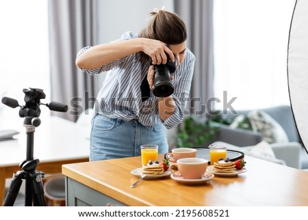blogging, profession and people concept - female food photographer with camera photographing pancakes, coffee and orange juice in kitchen at home