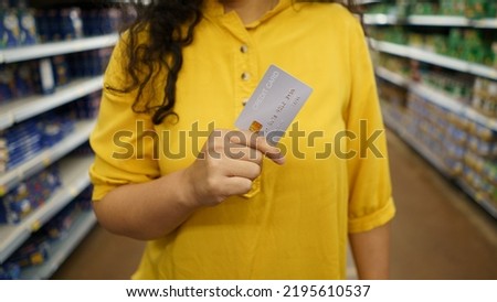 Woman at the supermarket she is paying credit card shopping concept. Credit card shopping in supermarket hand holding credit card payment.hand holding credit card blur supermarket store background.