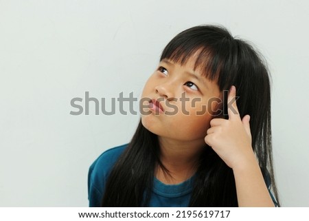 portrait of asian girl with straight black hair touching her head and expressing confusion thinking imagining dreaming good idea looking up isolated on white background. close up copy space.