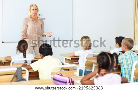 Female speaker giving lesson for primary school pupils in classroom Royalty-Free Stock Photo #2195625363