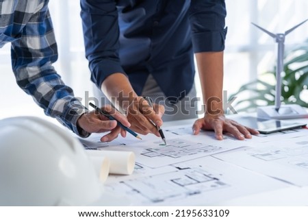 Asian man Close up blueprint architectural plans working together at table and discussing the floor plans.