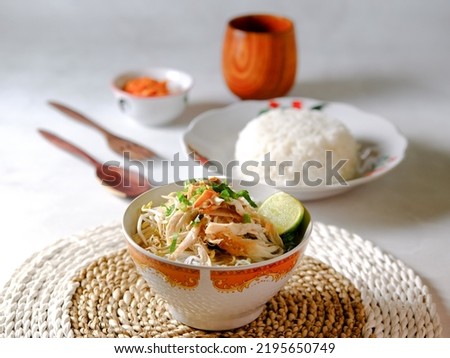 Indonesian Food Soto Ayam or Yellow Chicken Soup woth Rice, Chili Sauce, Cutlery and Wooden Cup in Blurry Background Royalty-Free Stock Photo #2195650749