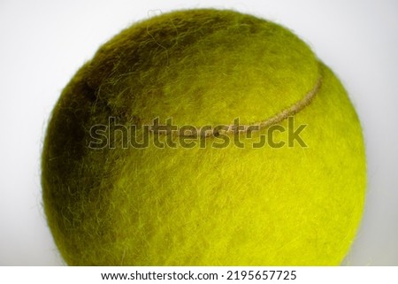 Extreme closeup of a portion of a tennis ball against a light background. Fuzzy yellow tennis ball with back light and side lighting