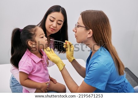 Nurse taking nasopharyngeal swab of Asian little girl for examination in medical laboratory to detect nose bacteria Royalty-Free Stock Photo #2195671253