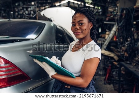 Portrait of woman auto mechanic holding clipboard at the repair garage. Repair service.