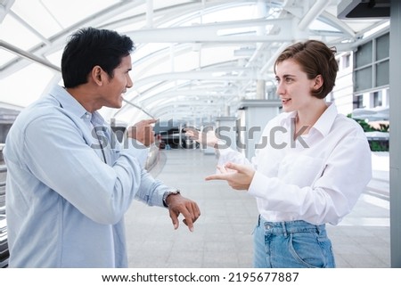 Angry Asian boyfriend pointing finger to watch to blame his girlfriend delay cus keep shopping at store or mall in urban city. Appointments and punctuality concept Royalty-Free Stock Photo #2195677887
