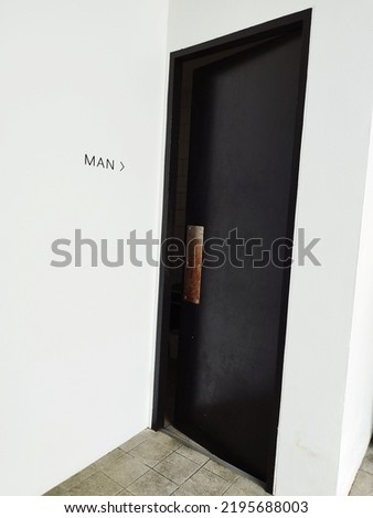Black Door, Entrance of male toilet. Public restroom with male toilet sign on white wall.