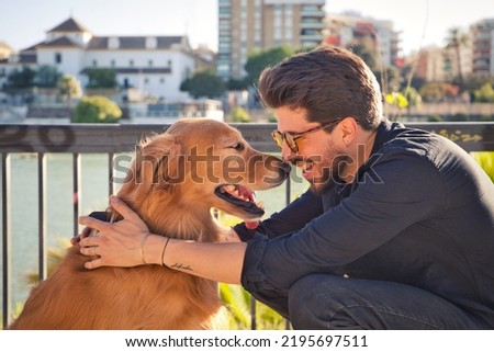 young latino man with sunglasses and beard and his brown golden retriever dog look at each other with love and affection. Concept pets, animals, dogs, love to retriever pets. Royalty-Free Stock Photo #2195697511
