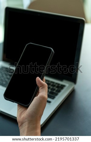 Close up shot of woman using smart phone and computer - stock photo