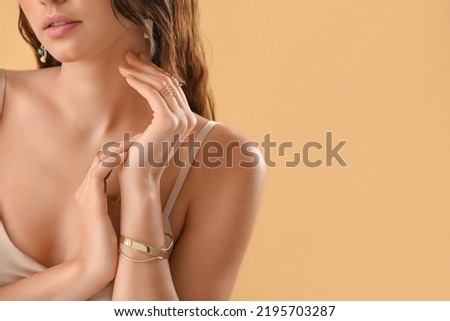 Beautiful young woman with stylish jewelry on beige background Royalty-Free Stock Photo #2195703287