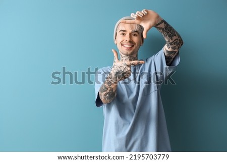 Young tattooed man on blue background Royalty-Free Stock Photo #2195703779