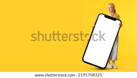 Mature woman and big smartphone on yellow background with space for text