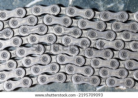 Closeup of Shiny Dirty Greasy Oiled Bicycle Chain As A Part of Metal Bicycle Equipment On Grey Tile Stony Background With Contrast Details.Horizontal image Composition