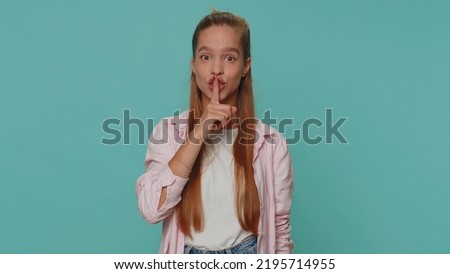Shh be quiet please. Pretty teenager scared girl presses index finger to lips makes silence gesture sign do not tells secret. Young female child kid isolated alone on blue studio background indoors