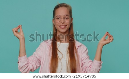 Keep calm down, relax, inner balance. Teenager young girl breathes deeply with mudra gesture, eyes closed, meditating with concentrated thoughts, peaceful mind. Student child kid on blue background