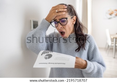 Woman is shocked from the rising energy costs and the bill she received for heat and electricity for her household. Royalty-Free Stock Photo #2195718707