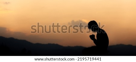 Silhouette of christian kneeling down and praying on mountain at sunset background. Christian concept.