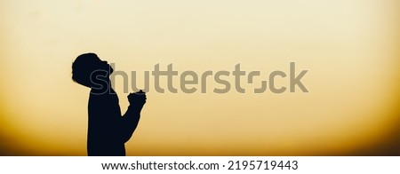 Silhouette of christian man praying to god at sunset. Christian Religion concept background. Copy space for individual text.