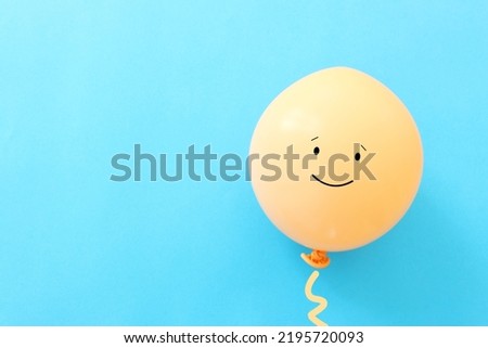 Top view image of balloon with happy face over blue background