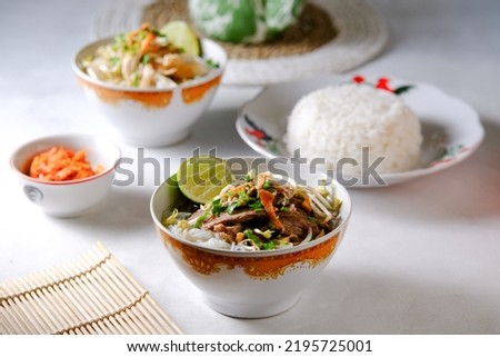 Indonesian Food Soto Daging or Beef Yellow Soup Served with Rice, Chili Sauce and Other Soup in Blurry Background Royalty-Free Stock Photo #2195725001