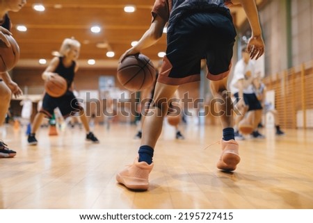 Junior level basketball player bouncing basketball. Young basketball player with classic ball. Basketball training session for youth. School sports class Royalty-Free Stock Photo #2195727415