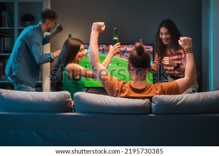 Group of young friends watching a football match on TV together and cheering for their team Royalty-Free Stock Photo #2195730385