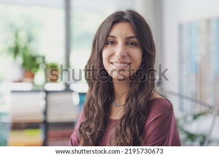 Happy young woman smiling and looking at camera, room interior with plants in the background Royalty-Free Stock Photo #2195730673