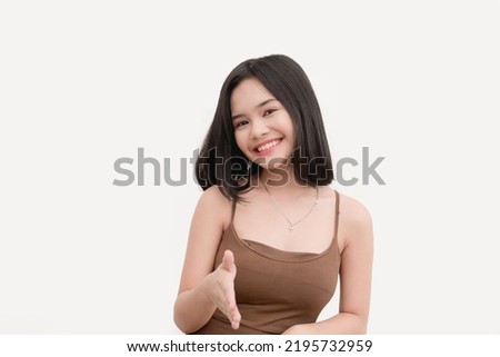 A friendly and affable teenage woman wearing a brown tank top offering a handshake isolated on a white background