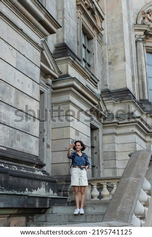 full length of happy tourist taking selfie on smartphone in front of building in berlin