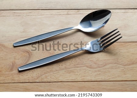Fork and spoon stainless steel kitchenware isolated on wooden background closeup.