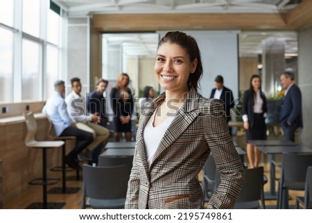 Portrait of happy female business teacher and professional coach. Beautiful young woman in jacket standing in office after corporate training class for team of employees, looking at camera and Royalty-Free Stock Photo #2195749861