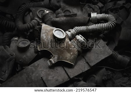 Gas mask in a dark room surrounded by other gas masks.  Royalty-Free Stock Photo #219576547