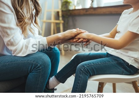 Young female school psychologist having serious conversation with smart little boy at office. Close up image mother and son palms, mommy holding hands of kid.  Concept of counsellor Royalty-Free Stock Photo #2195765709