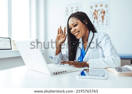 Young female doctor talking while having conference call at her office over a computer. Copy space. Head shot portrait woman doctor talking online with patient, making video call. 