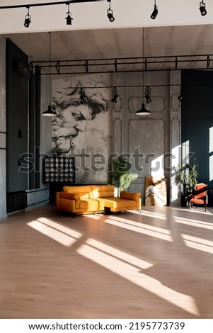 Modern loft living room with high ceiling, black and grey walls, wooden floor, design furniture and tropical plant. Royalty-Free Stock Photo #2195773739
