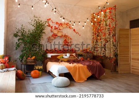 Autumn bedroom, living room interior. Red and yellow leaves and flowers in the vase and pumpkin on light background.