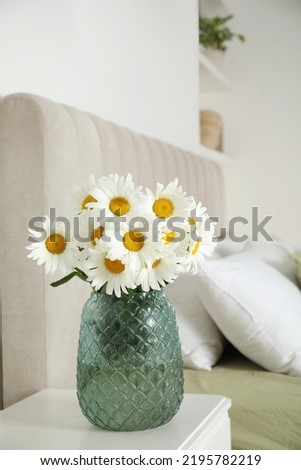 Bouquet of beautiful daisy flowers on nightstand in bedroom