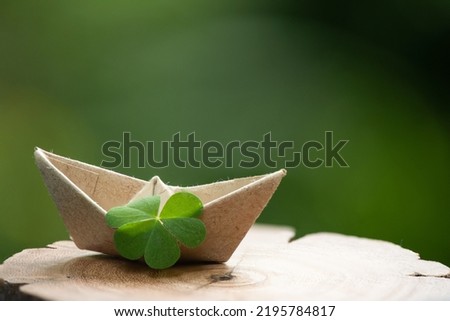 Clover leaf and paper boat on natute background.