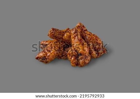 Breaded chicken wings with Jack Daniels sauce. A portion of the wings lies on a gray background.