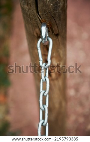 chain with links, carabiners and stainless steel anchors attached to a wooden post