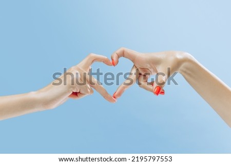Love. Graceful female hands gesturing heart shape isolated on blue background. Concept of relationship, feelings, community, care, support, symbolism, art. Copy space for ad