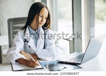 Cute little girl doctor wearing big lab coat and stethoscope